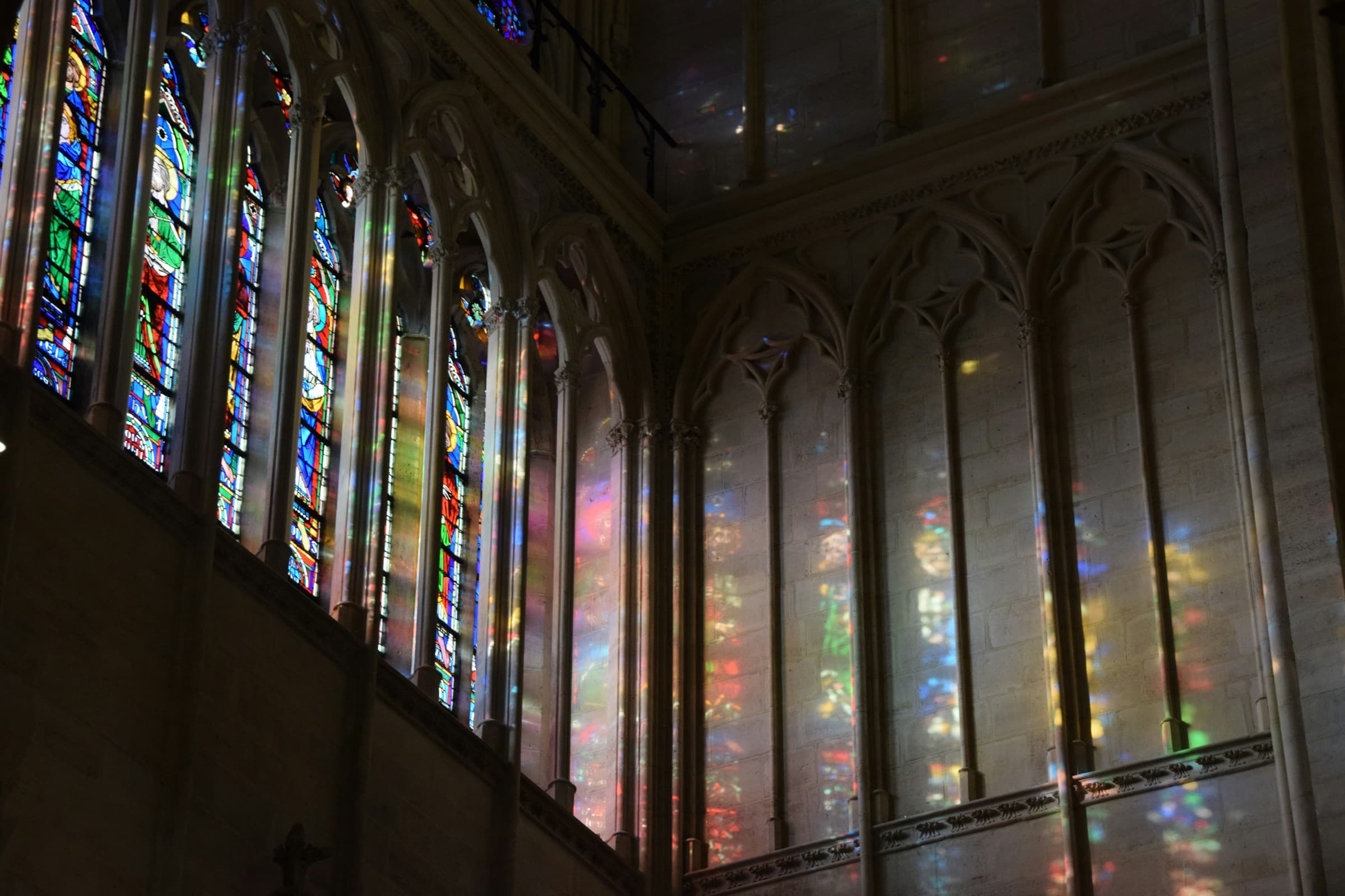 Sunlight streaming through stained-glass windows of a Catholic cathedral
